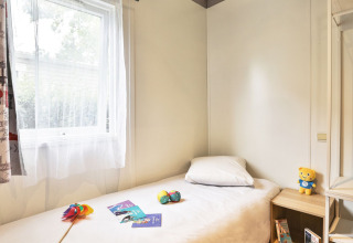 Heldere slaapkamer met eenpersoonsbed, speelgoed en raam in Relax Chalet Le Parc de la Grève, Frankrijk.
