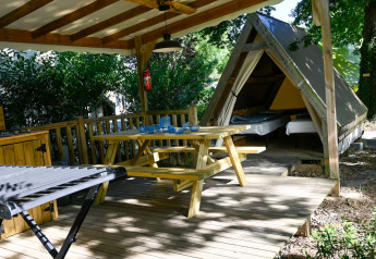 Tente safari Backpackers à Ushuaïa Villages Le Parc de la Grève, terrasse couverte et table en bois.