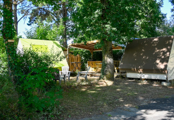 Safari telt og udendørs siddeområde i Ushuaïa Villages Le Parc de la Grève, omgivet af grønne træer.