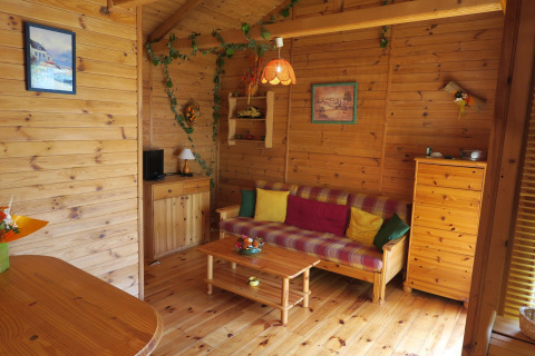 Indvendig udsigt til en hyggelig træhytte med farverige puder, trægulv og træmøbler i Ushuaïa Villages Le Parc de la Grève.