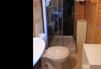Moderne badeværelse i træchalet på Ushuaïa Villages Le Parc de la Grève med brusekabine og toilet.