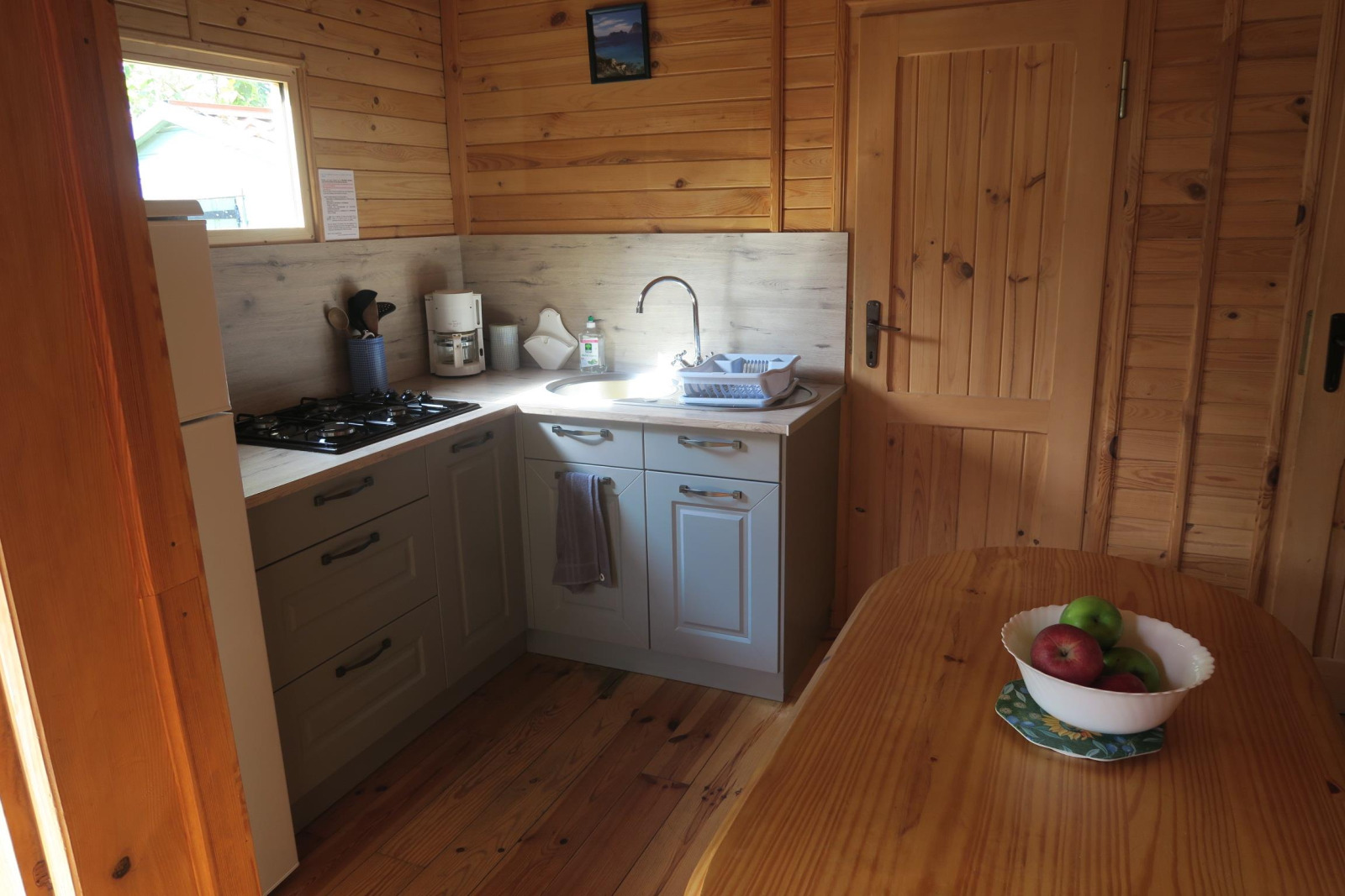 Gezellige houten chaletkeuken met fornuis, spoelbak en fruitschaal bij Ushuaïa Villages Le Parc de la Grève, Frankrijk.