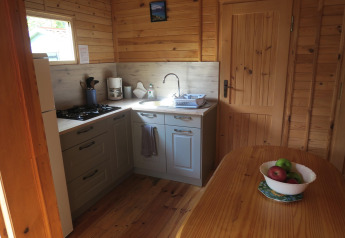 Hyggeligt køkken i træhytte med gaskomfur, vask, træbord og frugtskål på Wooden Chalet, Ushuaïa Villages Le Parc de la Grève, Frankrig.