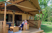 Madre e figlio si rilassano sulla veranda in legno di una tenda safari immersa nel verde della natura.