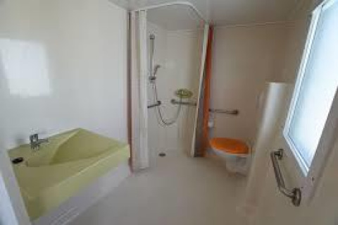 Bagno accessibile in una casa mobile al Flower Camping La Pointe du Talud, dotato di maniglioni e doccia.