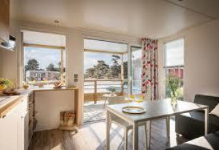 Intérieur lumineux d’un mobil-home Premium Living au Flower Camping La Pointe du Talud, vue sur la terrasse.