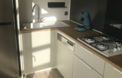 Moderne Küchenzeile mit Holzornamenten, Gasherd, Spüle und Kaffeemaschine im Mobilheim bei Camping La Pointe du Talud.