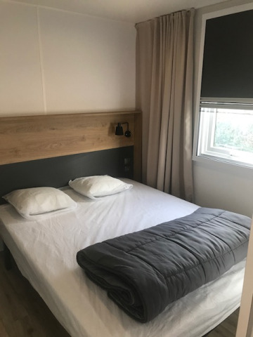 Schlafzimmer im Mobilheim „Premium EMBRUNS“ auf Flower Camping La Pointe du Talud, Bett mit Kissen und Decke.