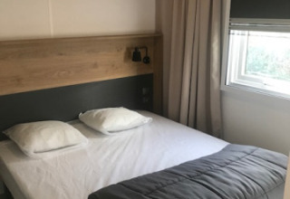 Bedroom at Mobile home ‘Premium EMBRUNS’ at Flower Camping La Pointe du Talud, with bed, pillows, and blanket.