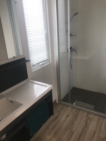 Modernes Badezimmer im Mobilheim mit Dusche, Waschbecken, Fenster und Holzfußboden im Flower Camping La Pointe du Talud.