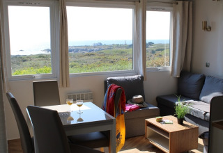 Cozy mobile home with stunning sea view, large windows, and comfy seating at La Pointe du Talud, France.