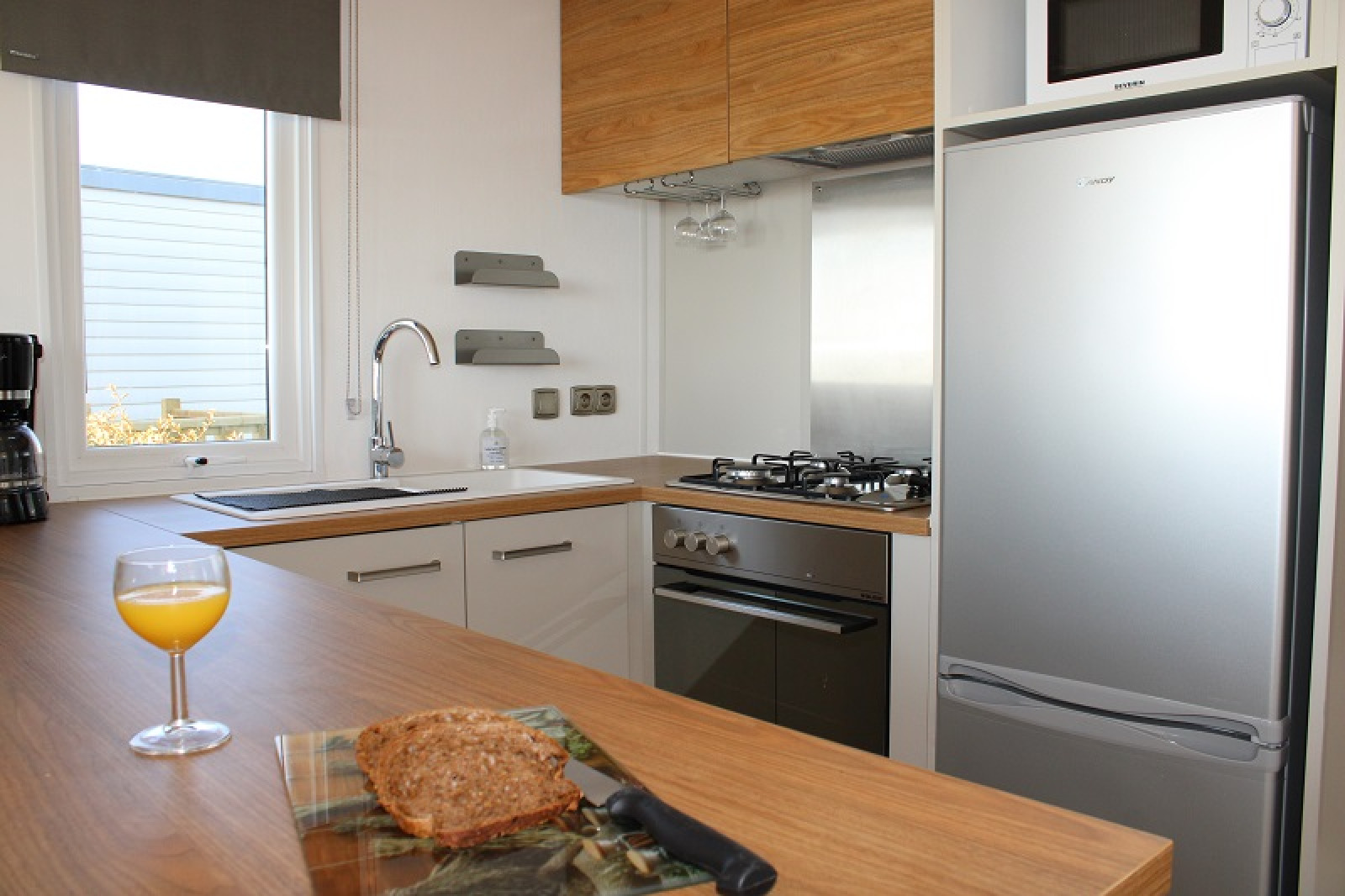 Moderne keuken in de Premium HORIZON stacaravan bij Flower Camping La Pointe du Talud met brood en sap.