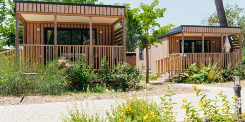 Dos modernos bungalows de madera, Cottage Next XL Loggia, en medio de vegetación en Trasimeno Glamping Resort, Italia.