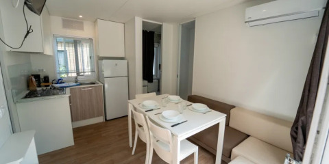 Cucina moderna e zona pranzo con aria condizionata nel Cottage Next XL Superior al Trasimeno Glamping Resort, Italia.