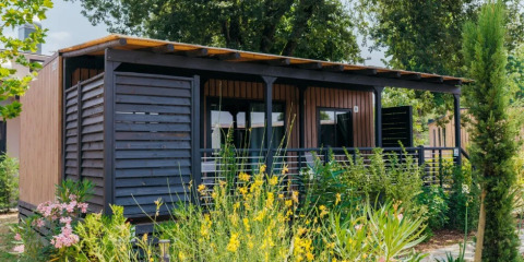 Vista esterna del Cottage Next XL Superior al Trasimeno Glamping Resort, immerso nel verde con design in legno moderno.