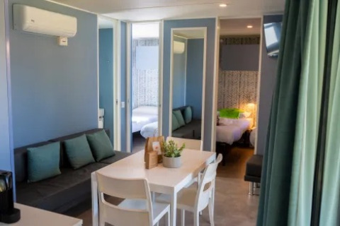 Vista interior del Cottage Next XXL Prestige en Trasimeno Glamping Resort, Italia, con mobiliario moderno.