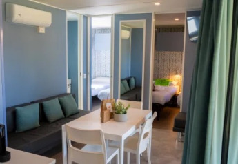 Vista interior del Cottage Next XXL Prestige en Trasimeno Glamping Resort, Italia, con mobiliario moderno.