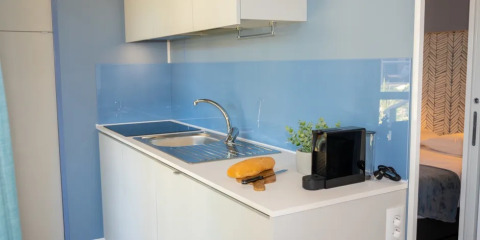 Cocina pequeña y moderna con fregadero, pan, cuchillo y cafetera en el Cottage Next XXL en Trasimeno Glamping Resort.