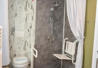Baño adaptado con ducha, asiento plegable y WC en Cottage Next XL 4 All, Trasimeno Glamping Resort.