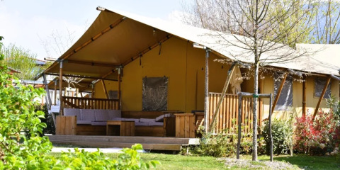 Safari-telt ved Trasimeno Glamping Resort i Italien, omgivet af grønt område og komfortabel terrasse.