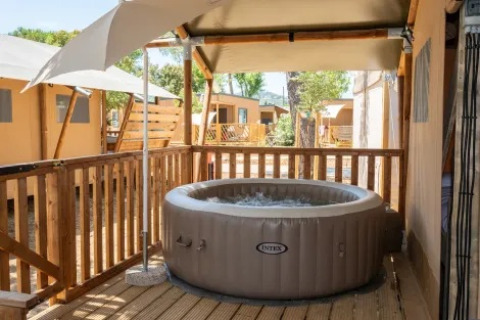 Jacuzzi exterior en terraza de madera en Safari Tent Comfort, Trasimeno Glamping Resort, Italia.