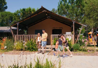 Famille devant la tente Safari Tent Comfort « Trasimeno » au Trasimeno Glamping Resort entourée de verdure.