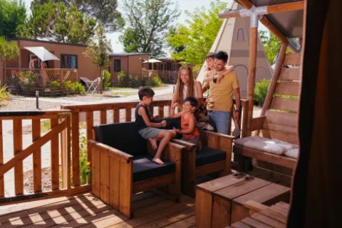 A family relaxes on the patio of a Safari Tent Comfort at Trasimeno Glamping Resort in Italy on a sunny day.