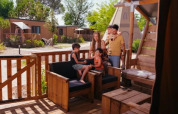 A family relaxes on the patio of a Safari Tent Comfort at Trasimeno Glamping Resort in Italy on a sunny day.