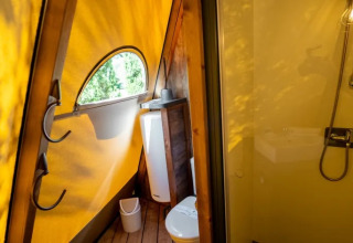 Badkamer in een Tipi Lodge tent met gele zeil en douche bij Trasimeno Glamping Resort, Italië.