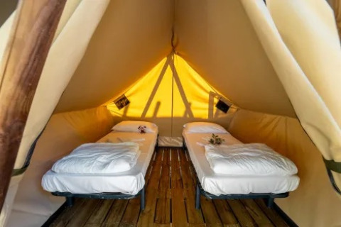 Binnenaanzicht van de Tipi Lodge tent bij Trasimeno Glamping Resort in Italië met twee eenpersoonsbedden.