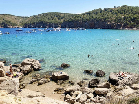 Panorama di Wecamp L'Escala Punta Mila, Catalogna, Spagna, con barche, nuotatori e acqua cristallina.