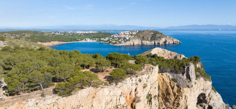Uitzicht op Wecamp L'Escala Punta Mila in Catalonië, Spanje, met kliffen, blauwe zee en groene dennen.