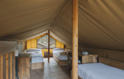 Interiør af safari telt Lodge Duplex Plus Montgrí med flere senge og træmøbler på Wecamp L'Escala Punta Mila.