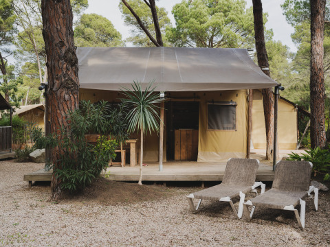 Safari tent Lodge Duplex Plus Montgrí met houten terras en loungestoelen in een bosrijke omgeving.
