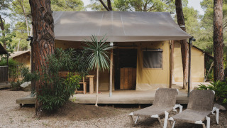 Safari tent Lodge Duplex Plus Montgrí met terras en ligstoelen, omgeven door bomen en natuur.