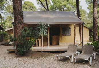 Safari tent Lodge Duplex Plus Montgrí met houten terras en loungestoelen in een bosrijke omgeving.