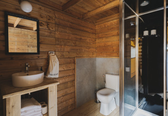 Badkamer in Lodge ‘Duplex Plus Montgrí’ met houten wanden, douche, lavabo en toilet bij Wecamp L'Escala Punta Mila.
