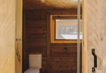Bagno con pareti in legno, wc e finestra in una tenda safari presso Lodge Family Plus Montgó, Wecamp L'Escala Punta Mila.
