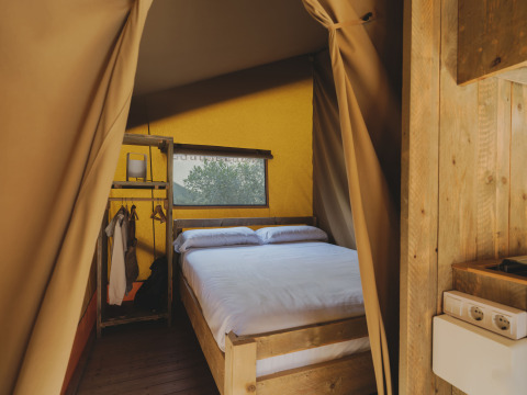 Interieur van de safari-lodge «Family Plus Montgó» bij Wecamp L'Escala Punta Mila met bed en open kast.