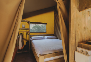 Interno della tenda safari Lodge «Family Plus Montgó» al Wecamp L'Escala Punta Mila con letto e armadio aperto.