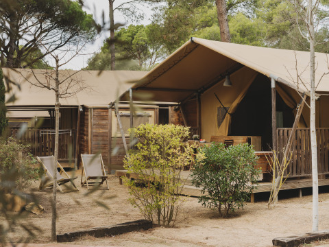 Buitenaanzicht van de Lodge Family Plus Montgó safaritent met houten terras, stoelen en natuurlijke omgeving.