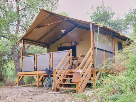Premium Lodge safaritent op Camping La Vallée Heureuse in Frankrijk, omgeven door bomen en natuur.