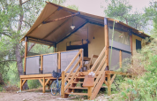 Premium Lodge safari tent at Campsite La Vallée Heureuse in France, set amongst lush greenery and trees.