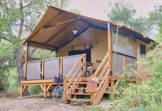 Premium Lodge safari tent at Campsite La Vallée Heureuse in France, set amongst lush greenery and trees.
