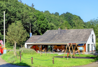 Ecolodge - Care accessible at Hameau de l'Ourthe in Belgium, showing a lodge, terrace, and playground area.