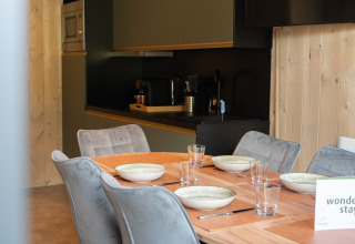Coin repas et cuisine de l'Ecolodge - Care accessible au Hameau de l'Ourthe en Belgique avec une décoration moderne.