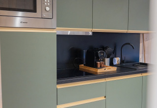 Modern kitchen at Ecolodge - Care accessible, Hameau de l'Ourthe, Belgium, featuring green cabinets and microwave.