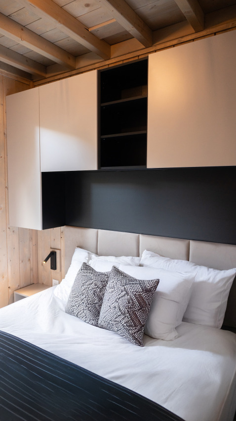 Dormitorio moderno en Ecolodge - Care accessible en Hameau de l'Ourthe, Bélgica, con vigas y decoración elegante.