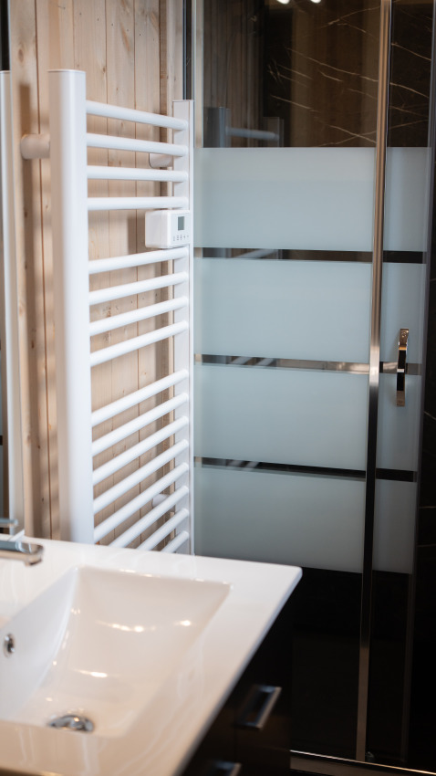 Salle de bain à Ecolodge - Care accessible au Hameau de l'Ourthe, Belgique avec lavabo, douche et sèche-serviettes.
