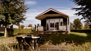 Foto der Group lodge: Eine gemütliche Hütte mit Veranda, Gartenmöbeln und viel Grün drumherum.